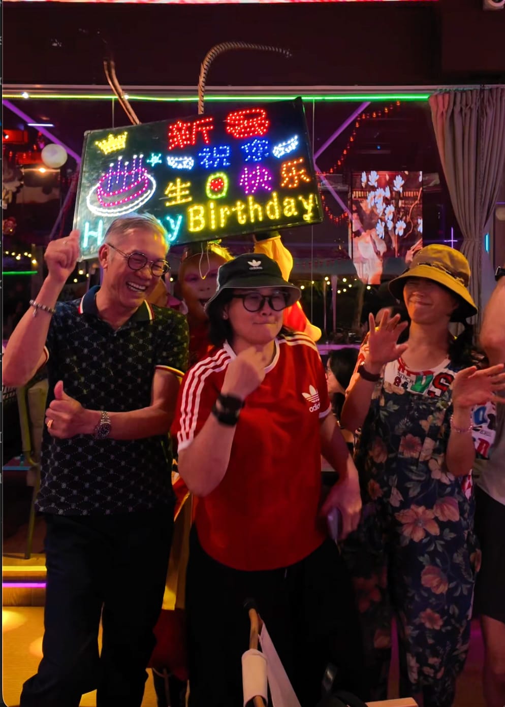 Guests celebrating a birthday under the neon Xin Yan sign