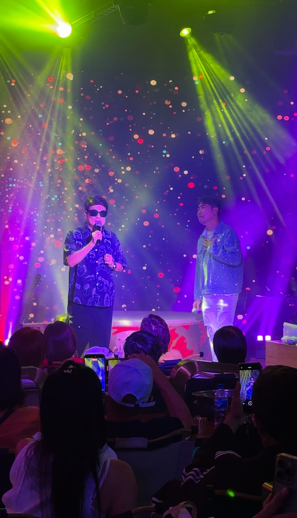 A singer performing on stage under colourful lights at Xin Yan