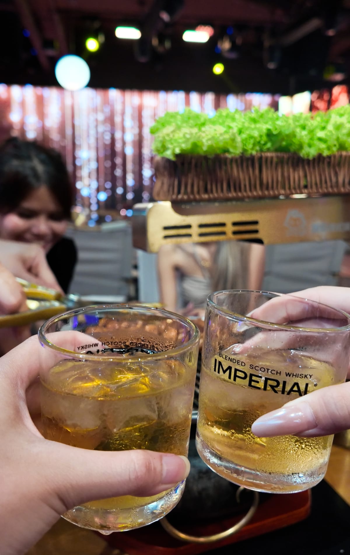 Friends raising glasses in a toast over the grill