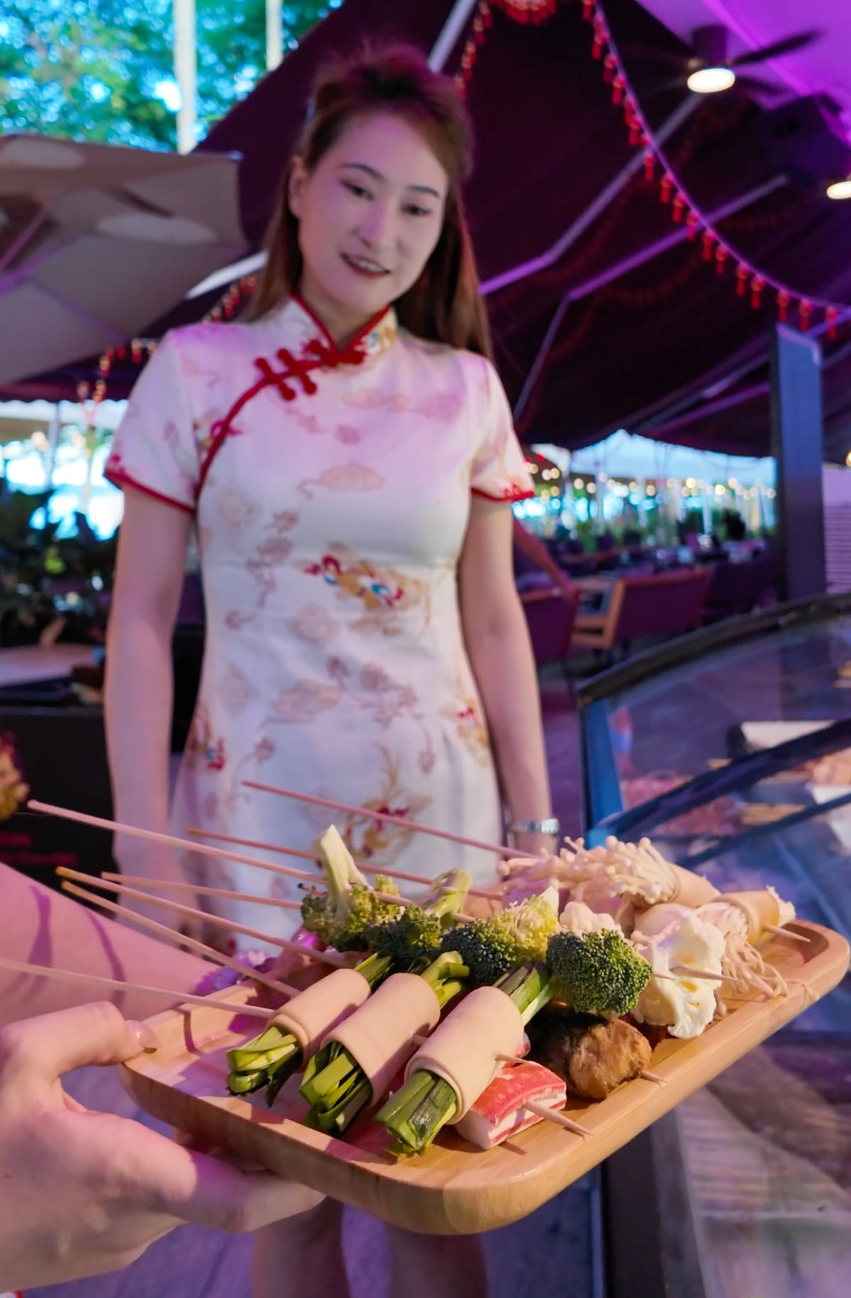 A server presenting a platter of grilled skewers at Xin Yan